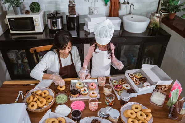 Menina ajudando sua mãe fazendo donuts — Fotografia de Stock