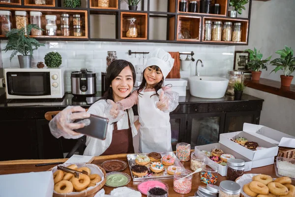 Attractive young woman and her little cute daughter are cooking on kitchen