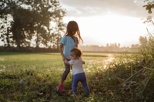 Hermana mayor juega con su hermana menor en los campos — Foto de Stock