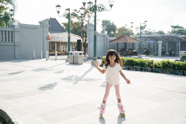Portrait of a happy and cheerful little girl playing roller skating in the park — Stock Photo, Image