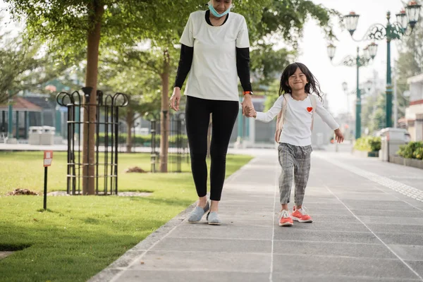 공원에서 어머니와 함께 걷고 있는 명랑하고 행복 한 어린 소녀의 모습 — 스톡 사진