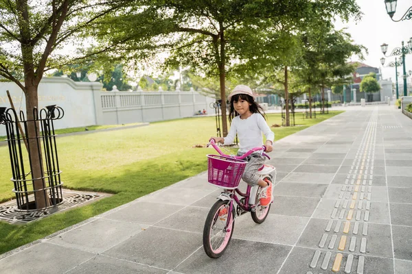 Egy vidám és boldog kislányról, aki biciklizik a parkban. — Stock Fotó