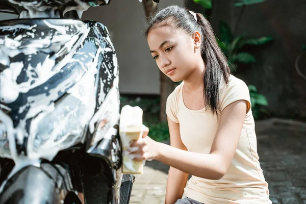 Ásia jovem menina lavagem seu moto scooter com sabão e esponja — Fotografia de Stock