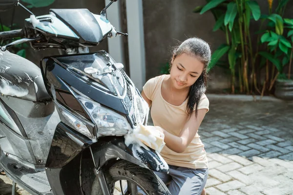 Ασιατικό νεαρό κορίτσι πλύσιμο σκούτερ μοτοσικλέτα του με σαπούνι και σφουγγάρι — Φωτογραφία Αρχείου