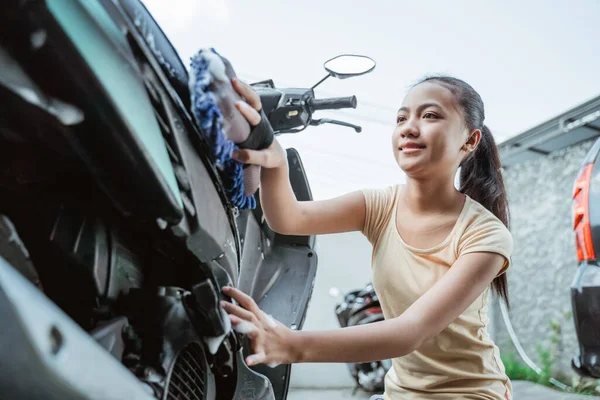 アジア系の少女がオートバイのスクーターを石鹸とスポンジで洗い — ストック写真