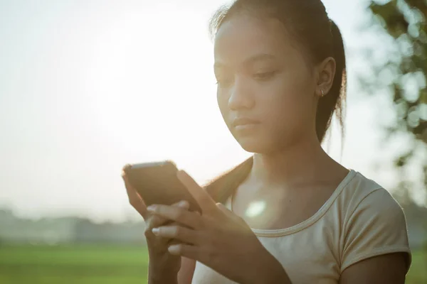 Close-up de uma jovem triste olhando enquanto segurando um celular — Fotografia de Stock
