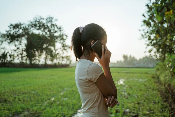 Portret van een mooi jong meisje op zoek terwijl het houden van een mobiele telefoon — Stockfoto