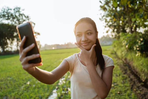 Retrato de uma bela jovem olhando enquanto segurando um celular tirar uma selfie — Fotografia de Stock