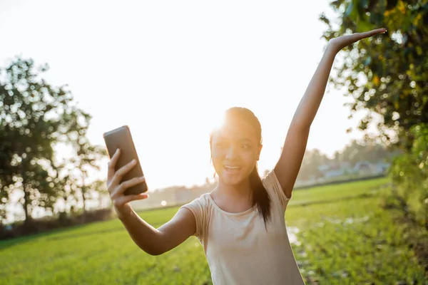 Portré egy gyönyörű fiatal lányról, aki a kezében tartja a mobilját, csinál egy szelfit — Stock Fotó