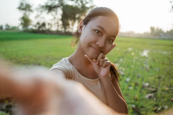 Retrato de una hermosa joven mirando mientras sostiene un teléfono celular tomar una selfie —  Fotos de Stock