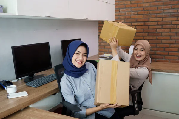 Attrayant joyeux jeune femme d'affaires musulmane travaillant sur ordinateur portable et souriant tout en étant assis à son bureau moderne avec son ami — Photo