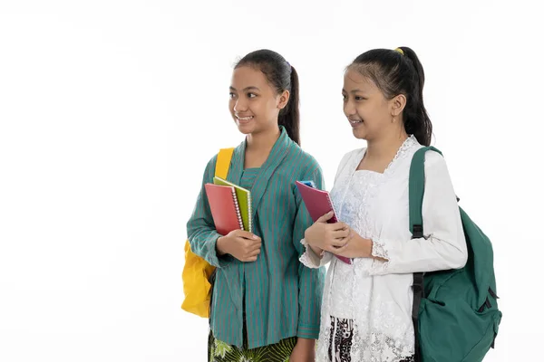 Twee jonge meisje dragen tas en boeken in traditionele kleding — Stockfoto