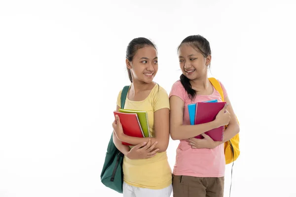 İki çift öğrenci, günlük giysiler içinde çanta ve kitaplar taşıyor. — Stok fotoğraf