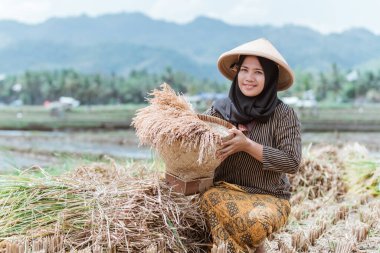 Asian Muslim female farmers raise their rice crops with woven bamboo baskets clipart