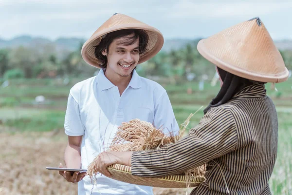 Los agricultores están contentos cuando muestran los rendimientos del arroz en bandejas de bambú tejidas a los agricultores masculinos utilizando tableta pc — Foto de Stock