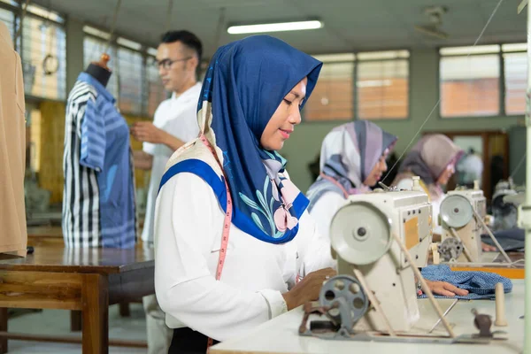 Närbild kvinnlig skräddare i hijab med hjälp av en symaskin under arbete — Stockfoto