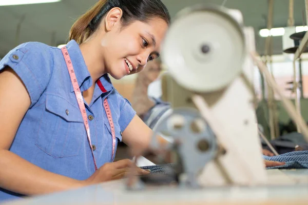 Fechar-se de uma mulher bonita sorrindo enquanto costura — Fotografia de Stock