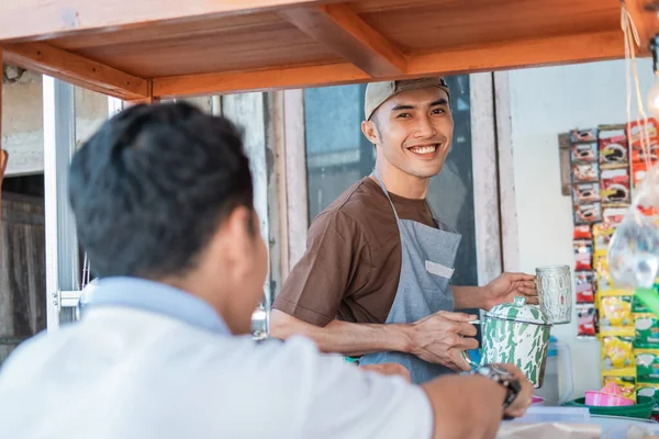 Angkringan araba satıcısı elinde demir bir bardakla gülümsüyor. — Stok fotoğraf