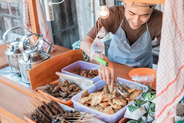 Carrinho loja homem sorriu enquanto segurando as pinças de comida para arrumar a exibição de alimentos — Fotografia de Stock