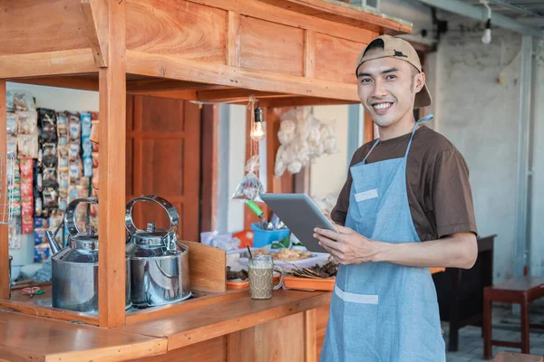 Vendedor masculino asiático en delantal sosteniendo una tableta pc — Foto de Stock