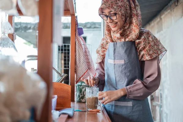 Asiático feminino angkringan vendedor com hijab e avental segurando um copo de bebida — Fotografia de Stock