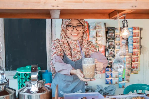Menina no hijab no avental serve café em um copo para os clientes — Fotografia de Stock