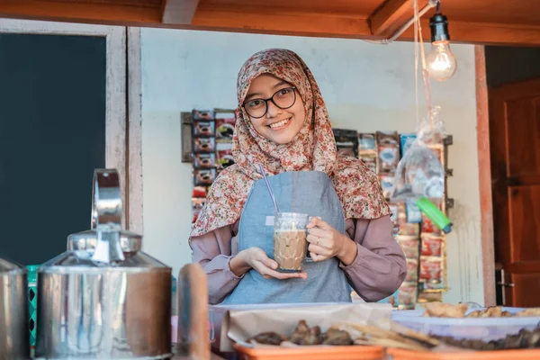 Dívka v hidžábu v zástěře se usmívá, zatímco drží sklenici kávy — Stock fotografie
