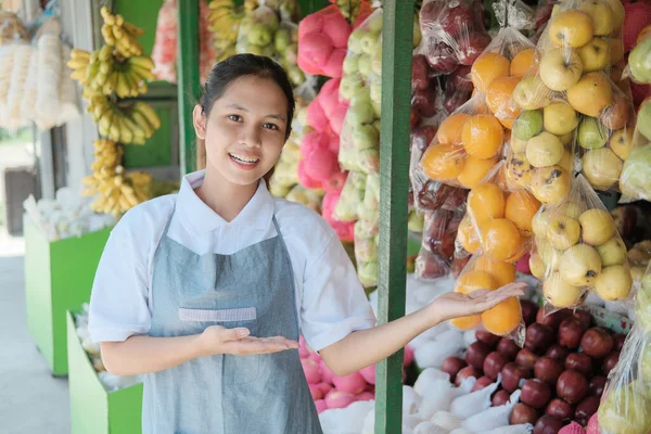 Mosolygó női eladó áll mellett egy kijelző friss gyümölcs — Stock Fotó