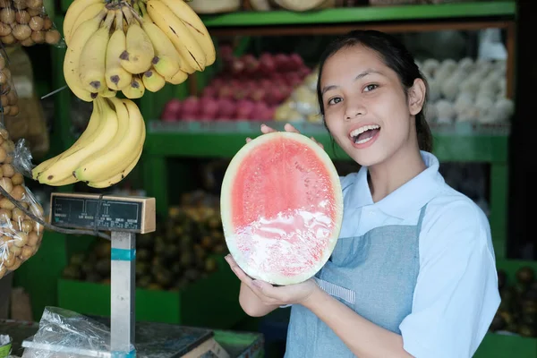 Eine halbe Wassermelone in der Hand einer Obstverkäuferin — Stockfoto