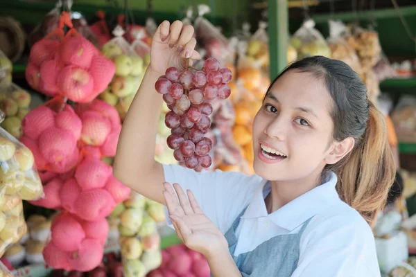 穿着围裙的亚洲女孩拿着葡萄 — 图库照片