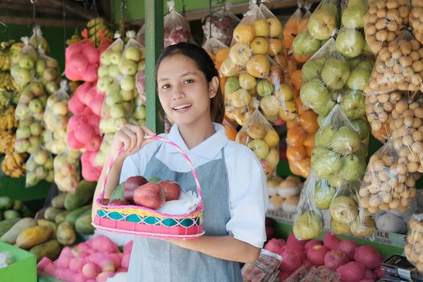 一个漂亮的女售货员，拿着柳条筐里的水果 — 图库照片