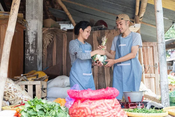 Vegetable seller wearing an apron stands carrying vegetables — Stock Photo, Image