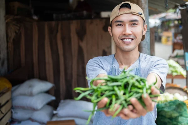亚洲卖菜的男人一边笑一边拿着绿辣椒 — 图库照片