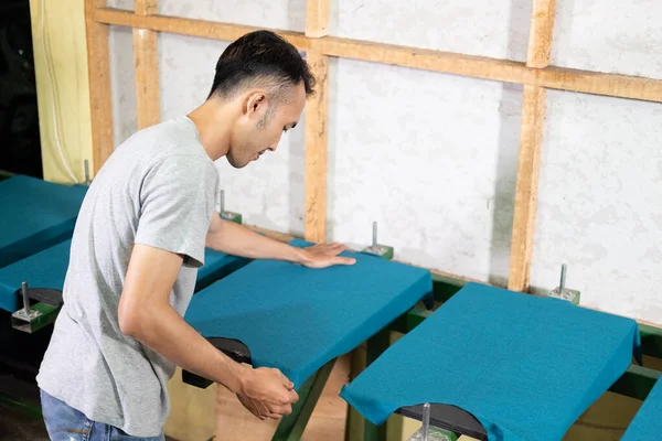Der männliche Mitarbeiter zieht das unebene Teil des Hemdes, während er das Hemd vorbereitet — Stockfoto