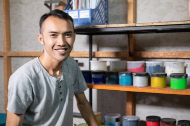 Asyalı erkekler ekranın önünde oturmuş boya rafları basarken gülümsüyor.