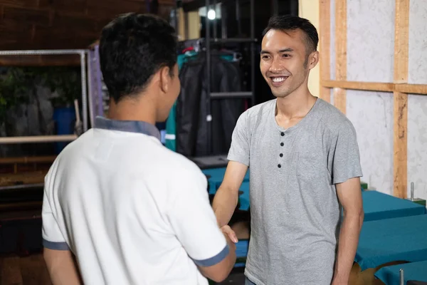 Sonriente asiático hombre propietario sacudiendo manos cuando cumplir con los clientes —  Fotos de Stock