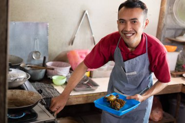 Aşçı, müşteriler için garnitürleri kızartmak için ocağı açarken gülümsedi.