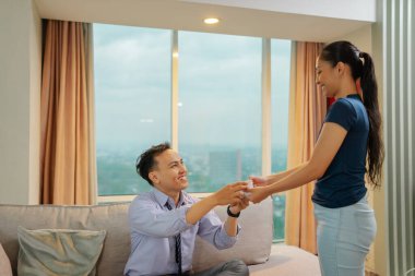 Sıcak ve sevgi dolu bir apartman dairesinde birbirlerine hediye veren neşeli bir çift.