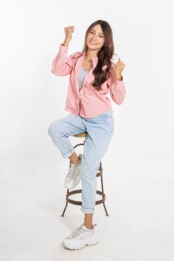 Neşeli ve mutlu bir kadın günlük giysiler içinde, enerjisini ve pozitifliğini sergiliyor.