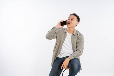 Neşeli genç bir adam neşeli bir telefon görüşmesi yaparken neşeli bir şekilde gülümsüyor.