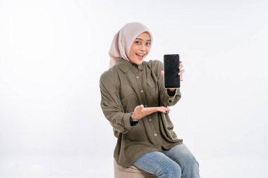 Neşeli bir kız akıllı telefonunu pozitiflik saçan canlı bir stüdyoda gösterir.