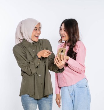 İki neşeli kadın, akıllı telefon kullanırken mutlu mesut vakit geçiriyorlar.