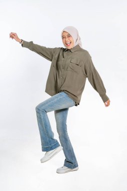 Neşeli genç bir kadın tesettür takarken günlük kıyafetleriyle neşeyle dans ediyor.