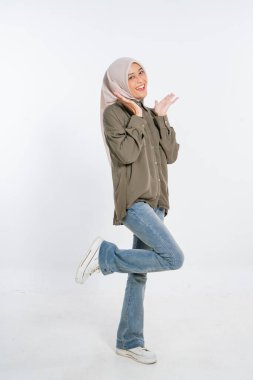 Neşeli genç bir kadın günlük kıyafetler ve şık bir başörtüsü giyerken neşeli poz verir.