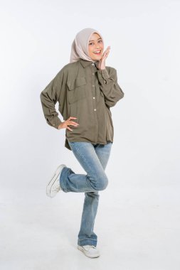 Neşeli genç bir kadın, sıradan giyinmiş, harika bir şekilde neşeli ve parlak bir gülümsemeyle poz veriyor.