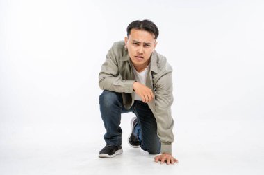 Çok şık giyinmiş modaya uygun genç bir adam yoğun ve büyüleyici bir bakışla çömeliyor.