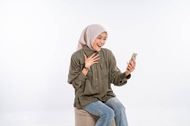 tesettürlü mutlu kadın telefonunu kullanarak gülümsüyor, neşe ve heyecan ifade ediyor..