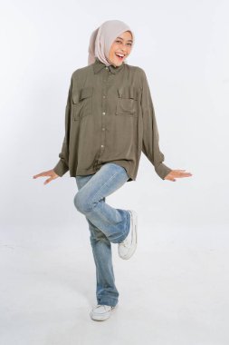 Renkli başörtüsü takan neşeli ve kendinden emin genç bir kadın günlük kıyafetleriyle mutlu poz verir.