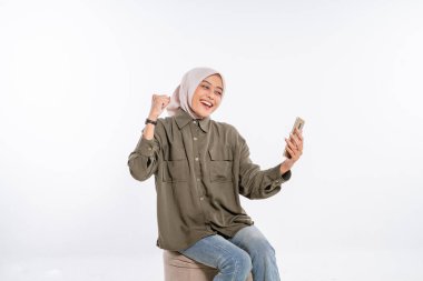 Renkli tesettürlü neşeli bir kadın akıllı telefonuyla mutlu bir selfie çekiyor.