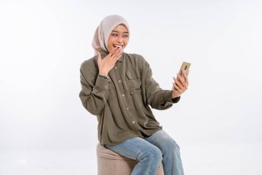 Taburede oturan mutlu bir kadın, telefonuyla selfie çekerken gülümsüyor..